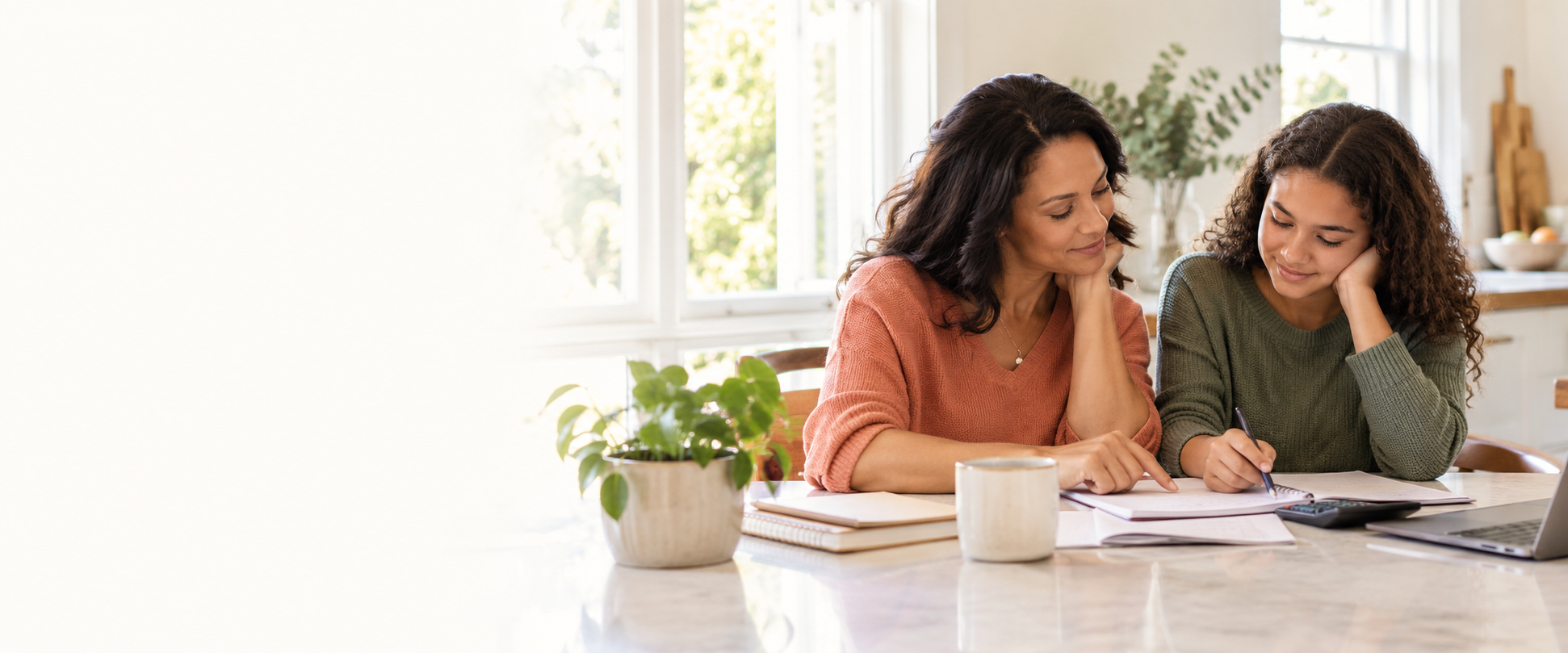 A parent and teen calmly planning money together at a bright kitchen table